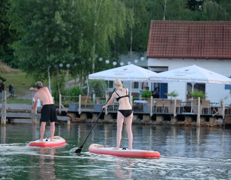 Zwei Menschen betreiben Stand-Up-Paddling am Hainer See.